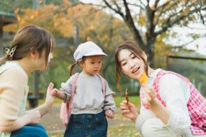 公園で保育士が子どもに葉っぱを見せている