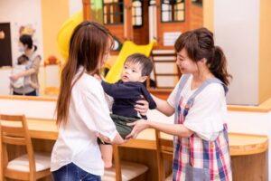 子供を預ける母と保育士