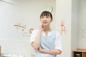 腕を組んで悩む保育士